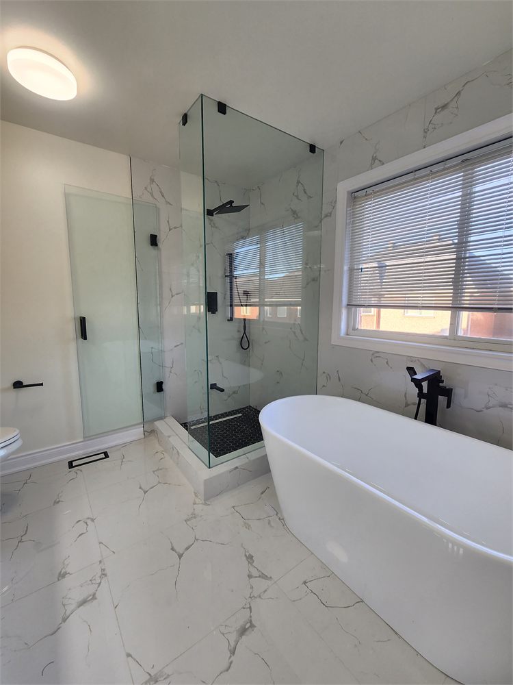 Finished bathroom with a freestanding tub, glass corner shower and marble-look tile