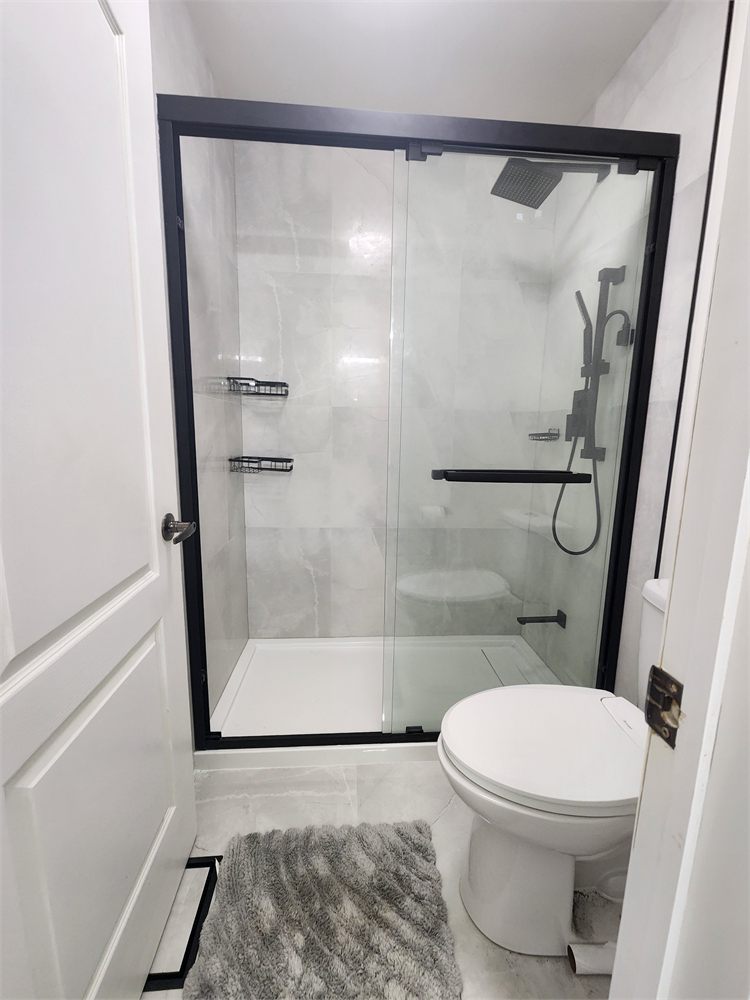Finished shower with a black-framed sliding glass door and large grey tile