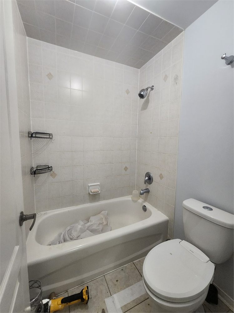 Dated tub and shower with beige wall tile, before the remodel