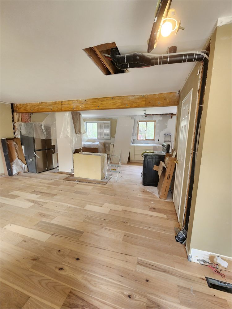 New hardwood flooring running under an opened wall with a structural beam