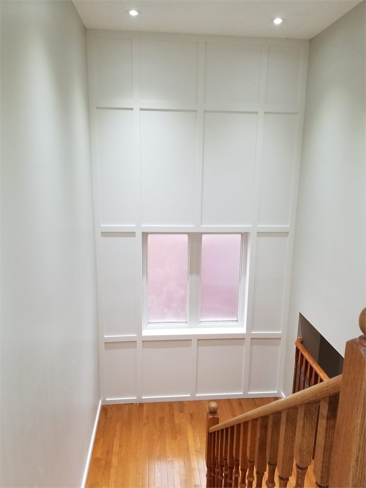 Floor-to-ceiling white panel wainscoting around a stairwell window
